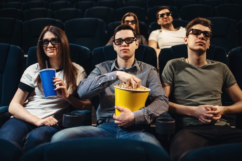 People with popcorn watching movie in cinema